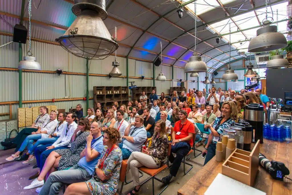 Mensen aandachtig luisterend naar een presentatie tijdens een vrolijk congrestival bij UP Events.